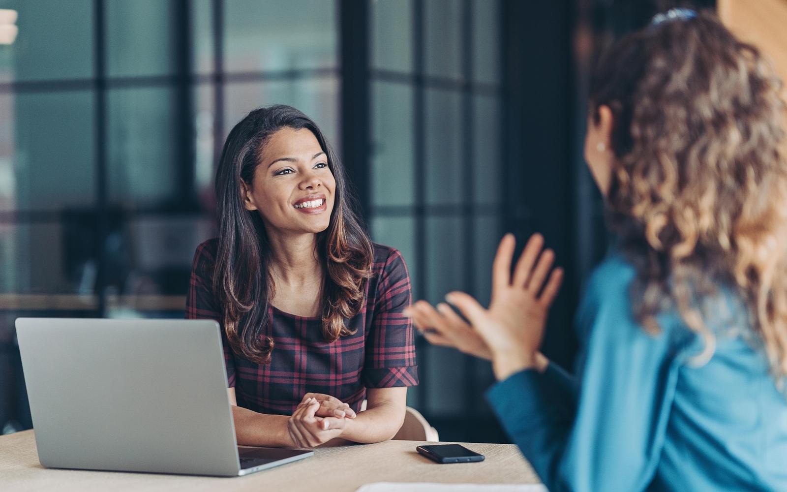 Businesswomen talking in the office with a laptop on the desk