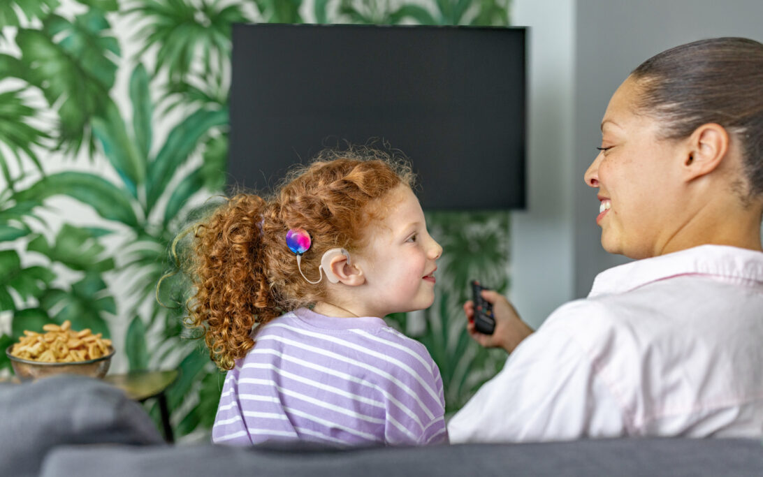A mother and daughter with a cochlear implant watching TV