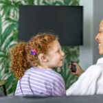 A mother and daughter with a cochlear implant watching TV