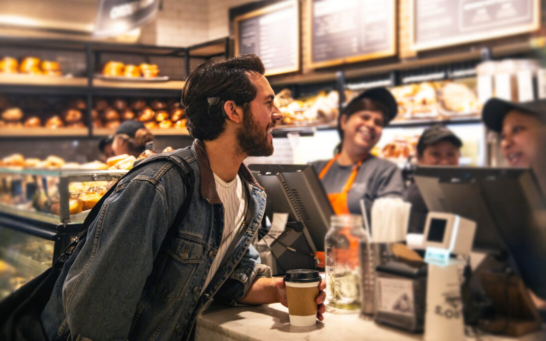 A man with a cochlear implant talking to the cashier of a bakery