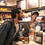 A man with a cochlear implant talking to the cashier of a bakery