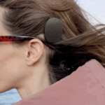 Carly wearing a cochlear implant on the beach after eight years of living with single-sided deafness.