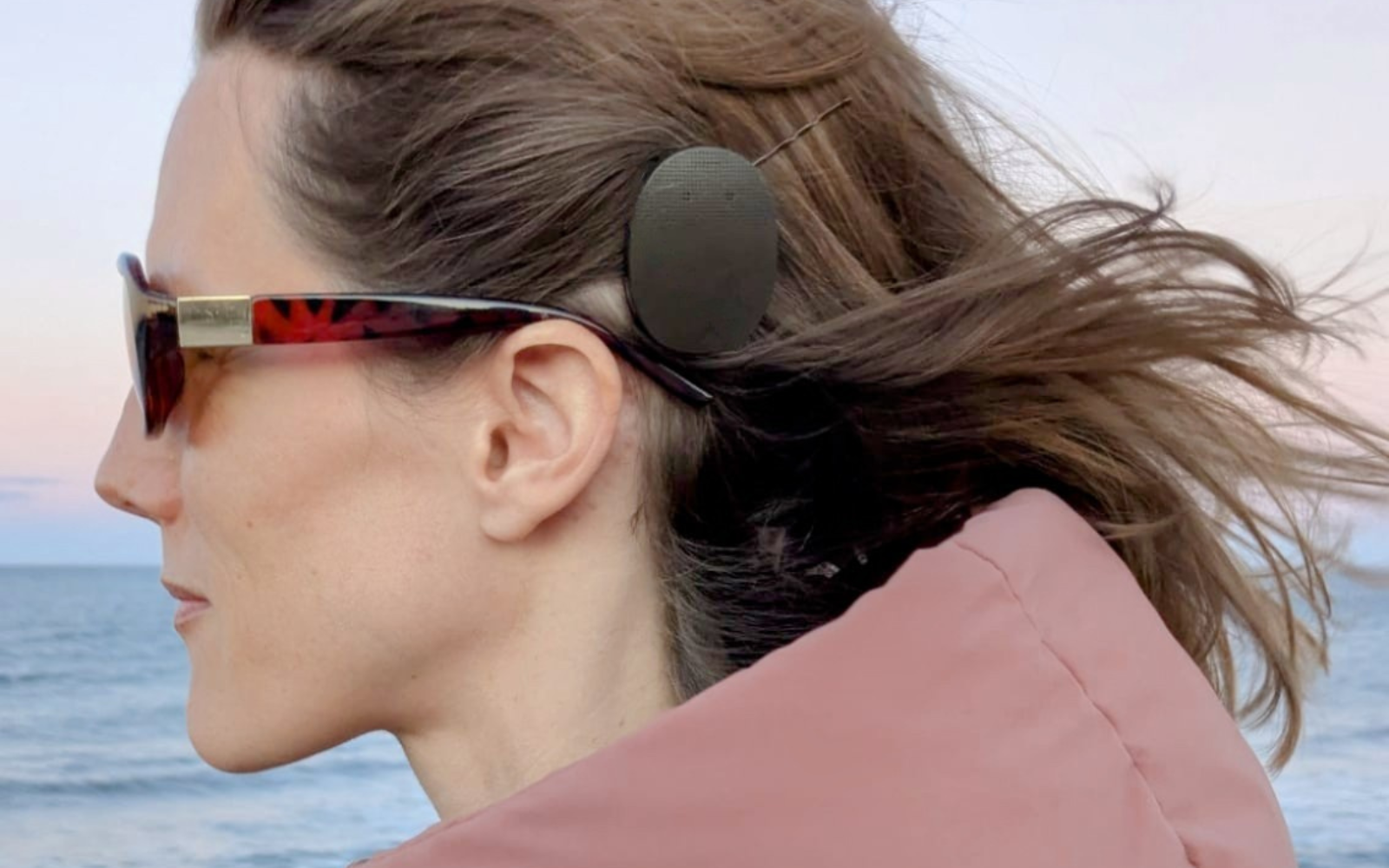 Carly wearing a cochlear implant on the beach after eight years of living with single-sided deafness.