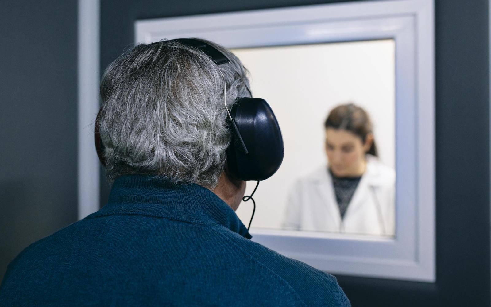 An older man gets his hearing tested for presbycusis by an audiologist