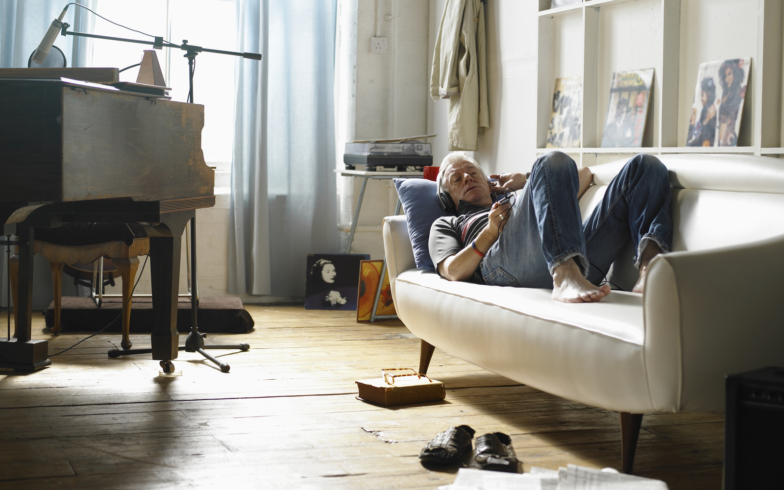 Mature man lying on couch listening to music