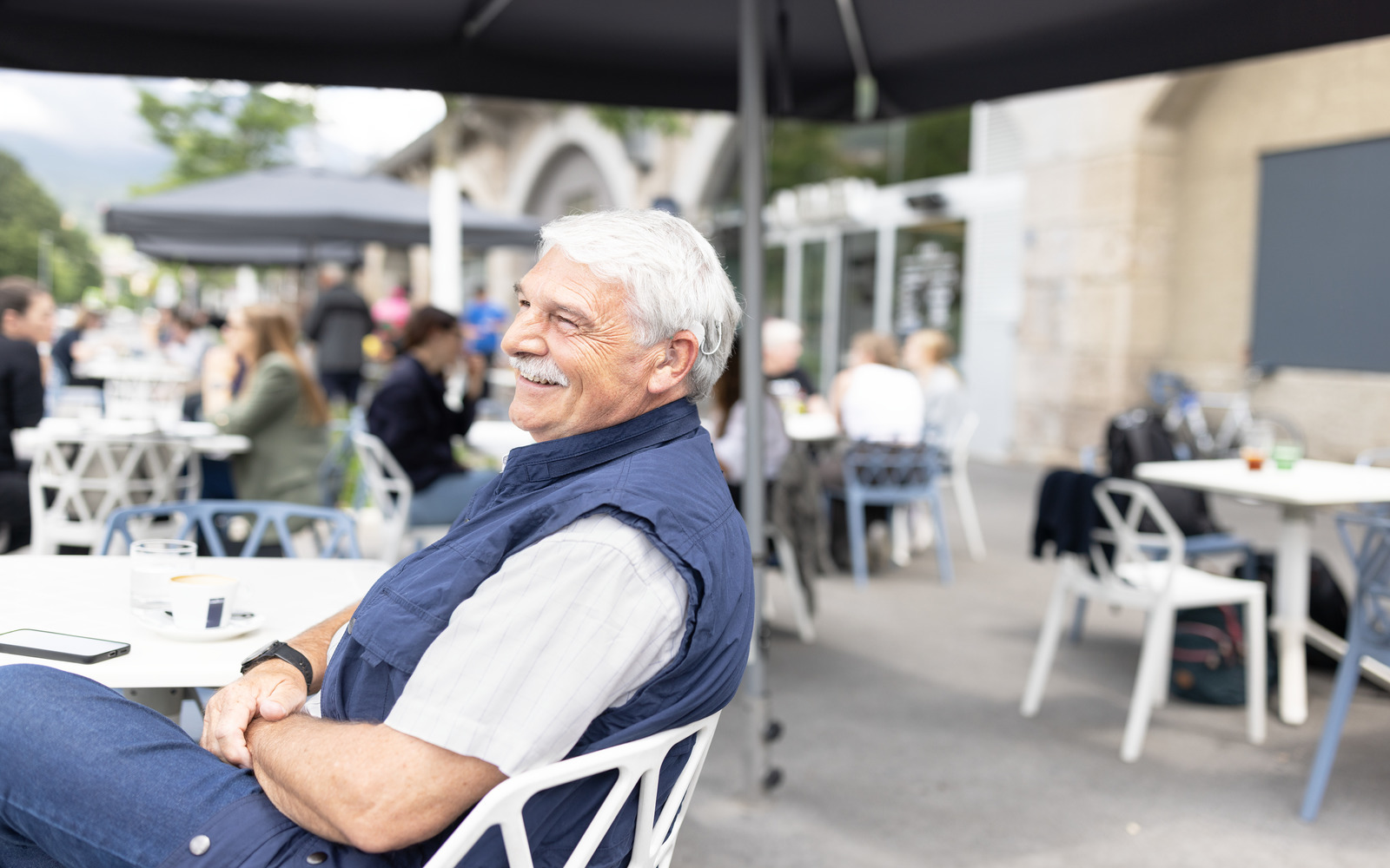 Ein Mann mit Cochlea-Implantat sitzt in einem Café.