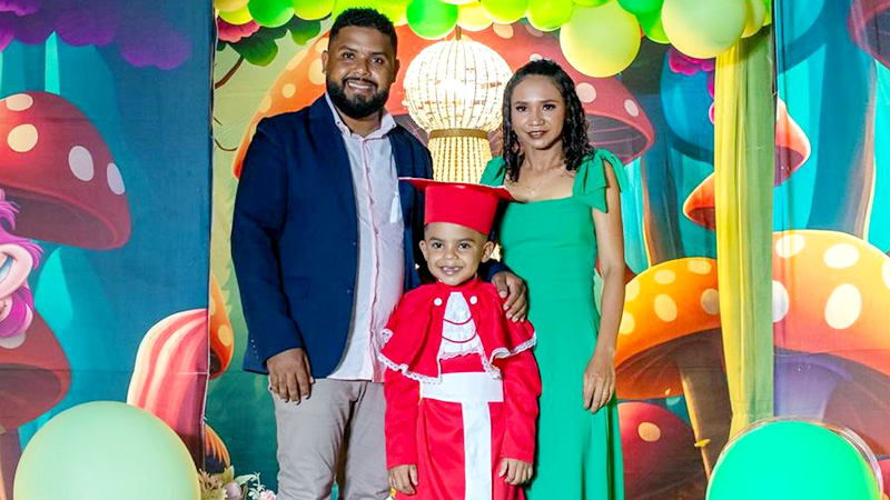 Davi e seus pais posando para foto de sua formatura do jardim de infância