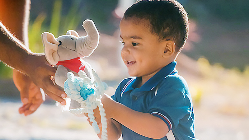 Davi brincando com a pelúcia Mellie em um dia ensolarado