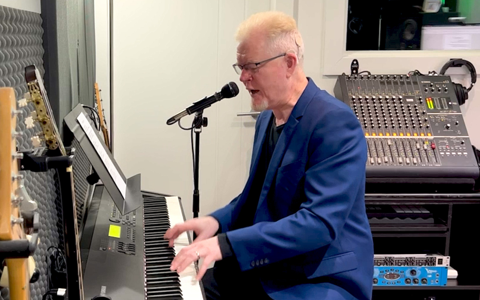 A CI user playing piano with his audio processor visible