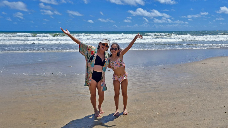 Clara com implante coclear e sua mãe na praia