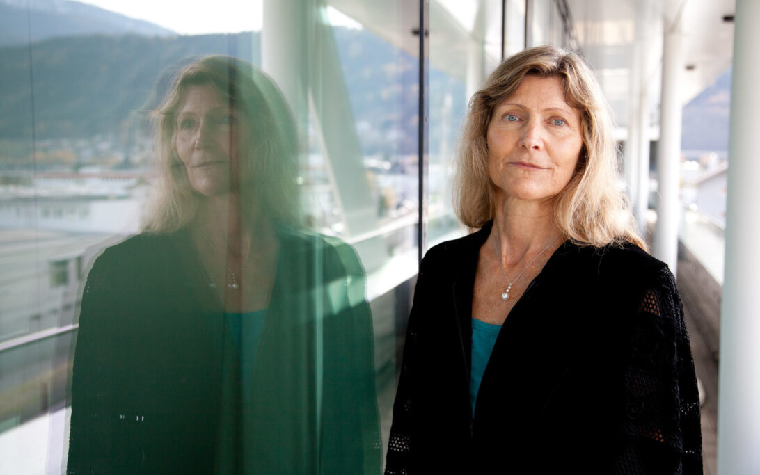Ingeborg Hochmair looks at the camera, with her image reflected in the window to her left