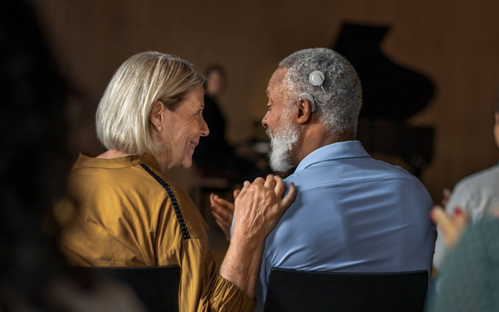 Couple talk to each other during a concert. The man has an audio processor