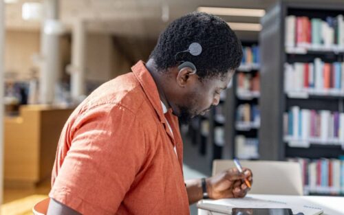 A man with an audio processor studies in a library