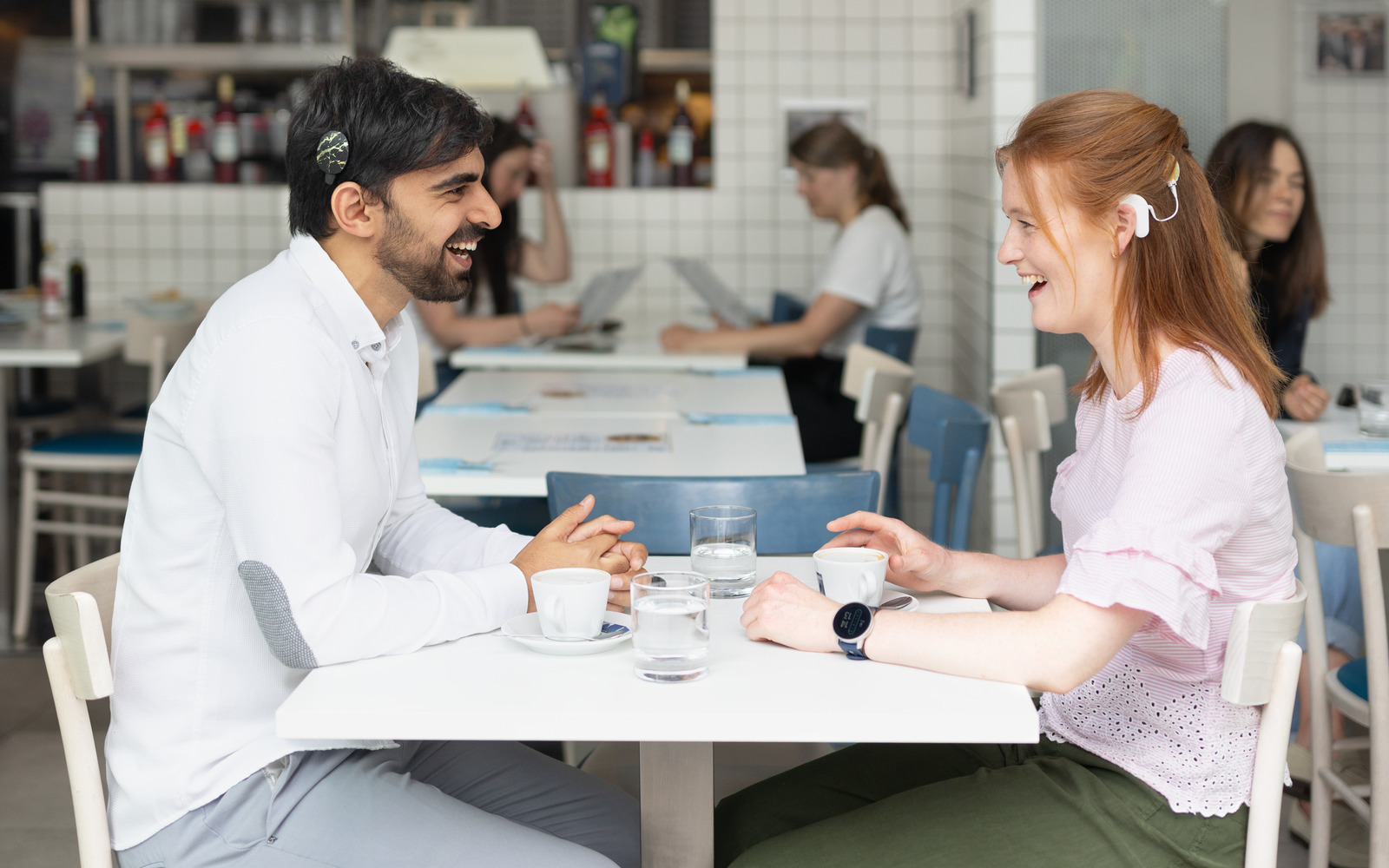 Two people with cochlear implants sitting in a restaurant and talking