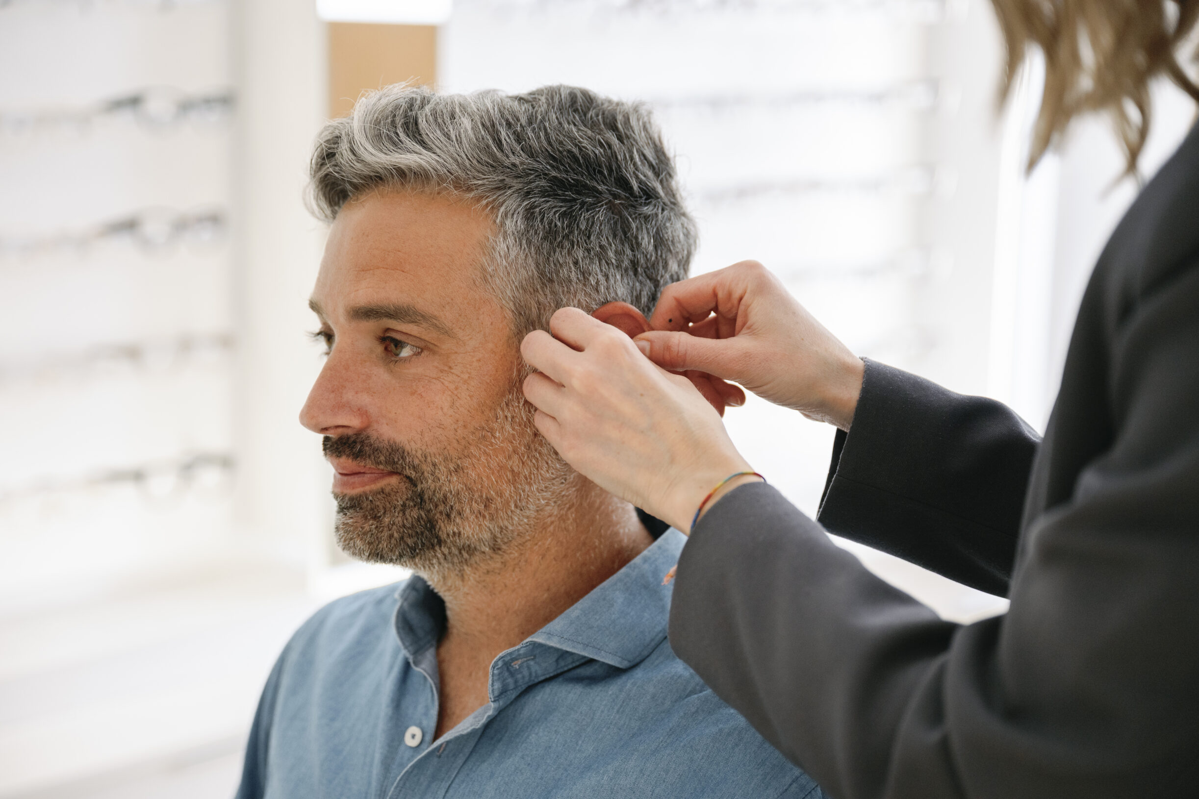 A man having a hearing aid fitted by a professional in a shop