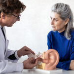 An older woman talking to an ENT with the model of an ear in front of them