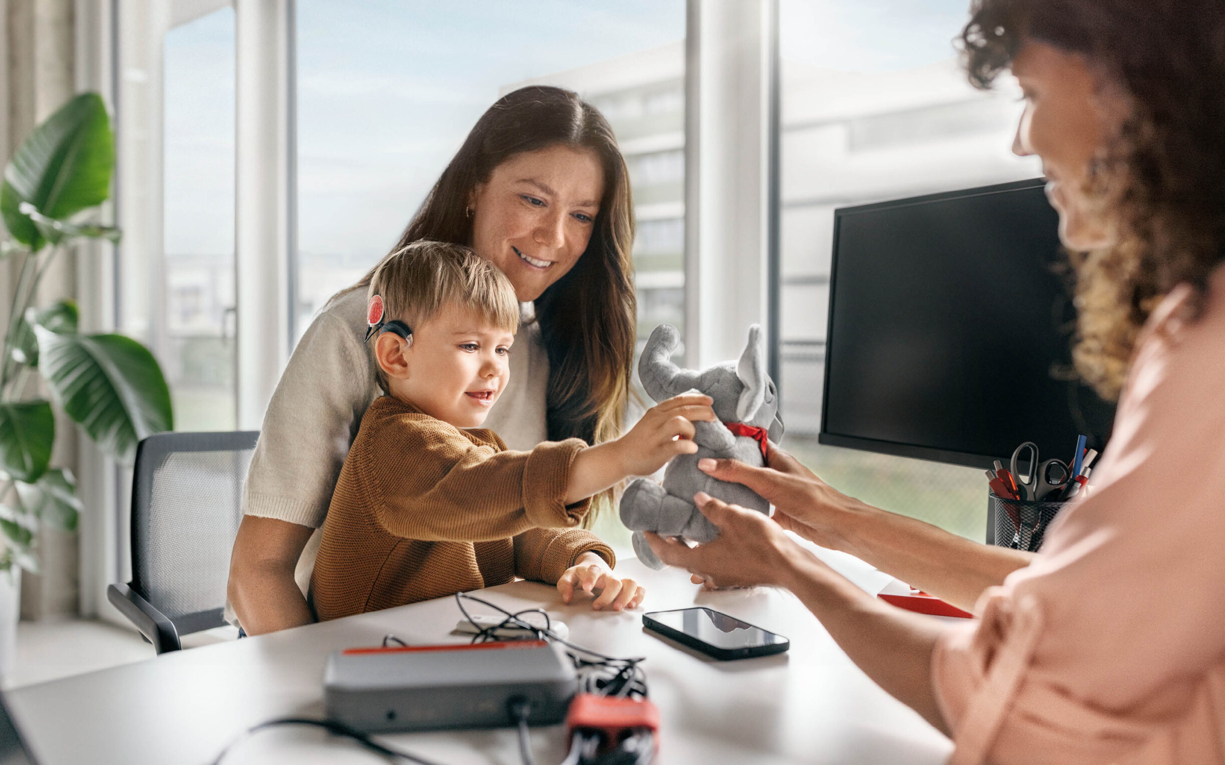 A toddler and his mom during an appointment with an audiologist