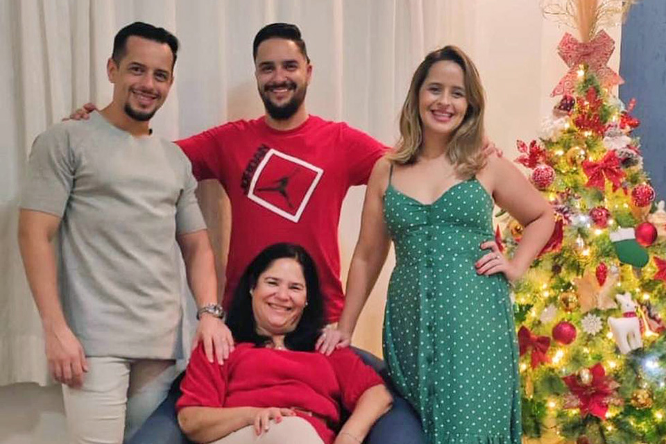 Arthur e sua família reunidos, árvore de Natal decorada ao lado.