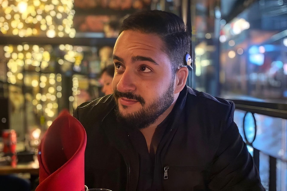 Arthur sentado à mesa de restaurante em ambiente noturno.